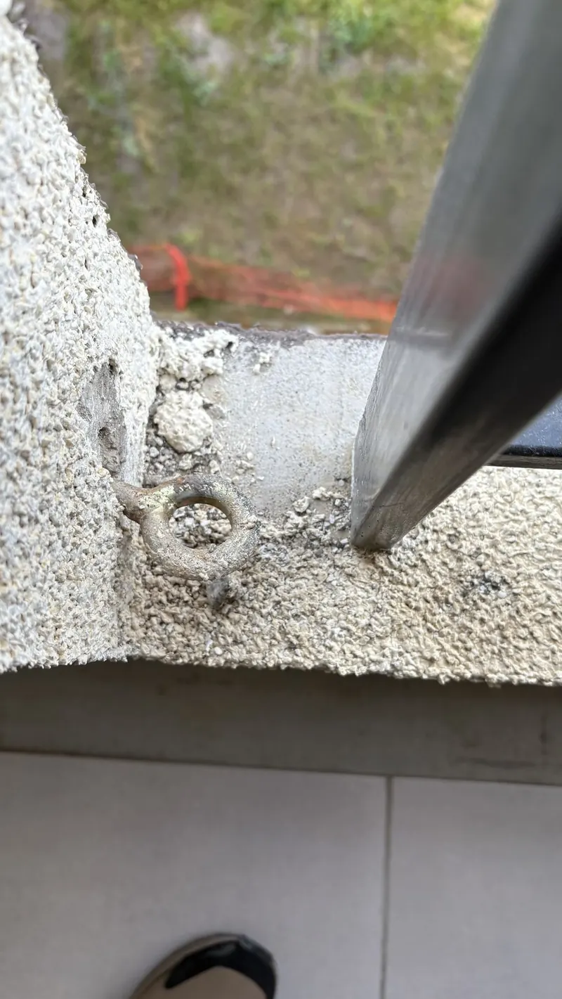 Anclaje metálico en antepecho exterior revisado durante una inspección